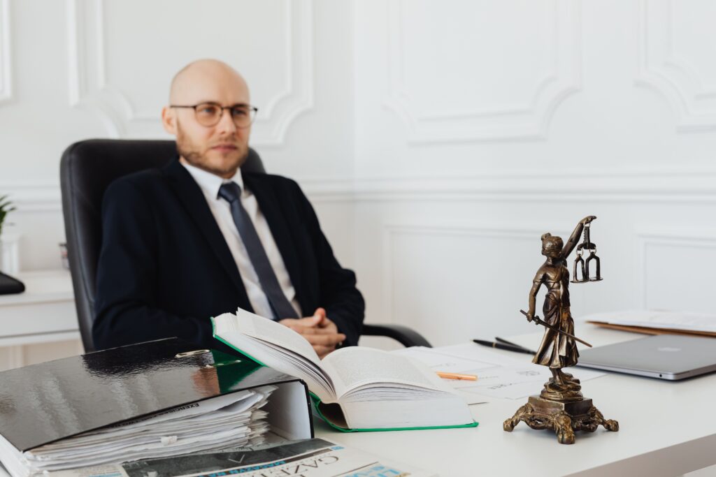Lawyer in a suit at a desk with documents and a Lady Justice statue