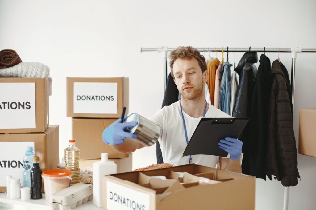 Volunteer packing donation boxes beside a clothing rack