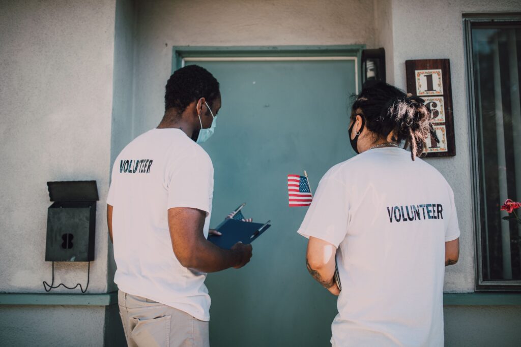 Two volunteers in matching vests at a doorway